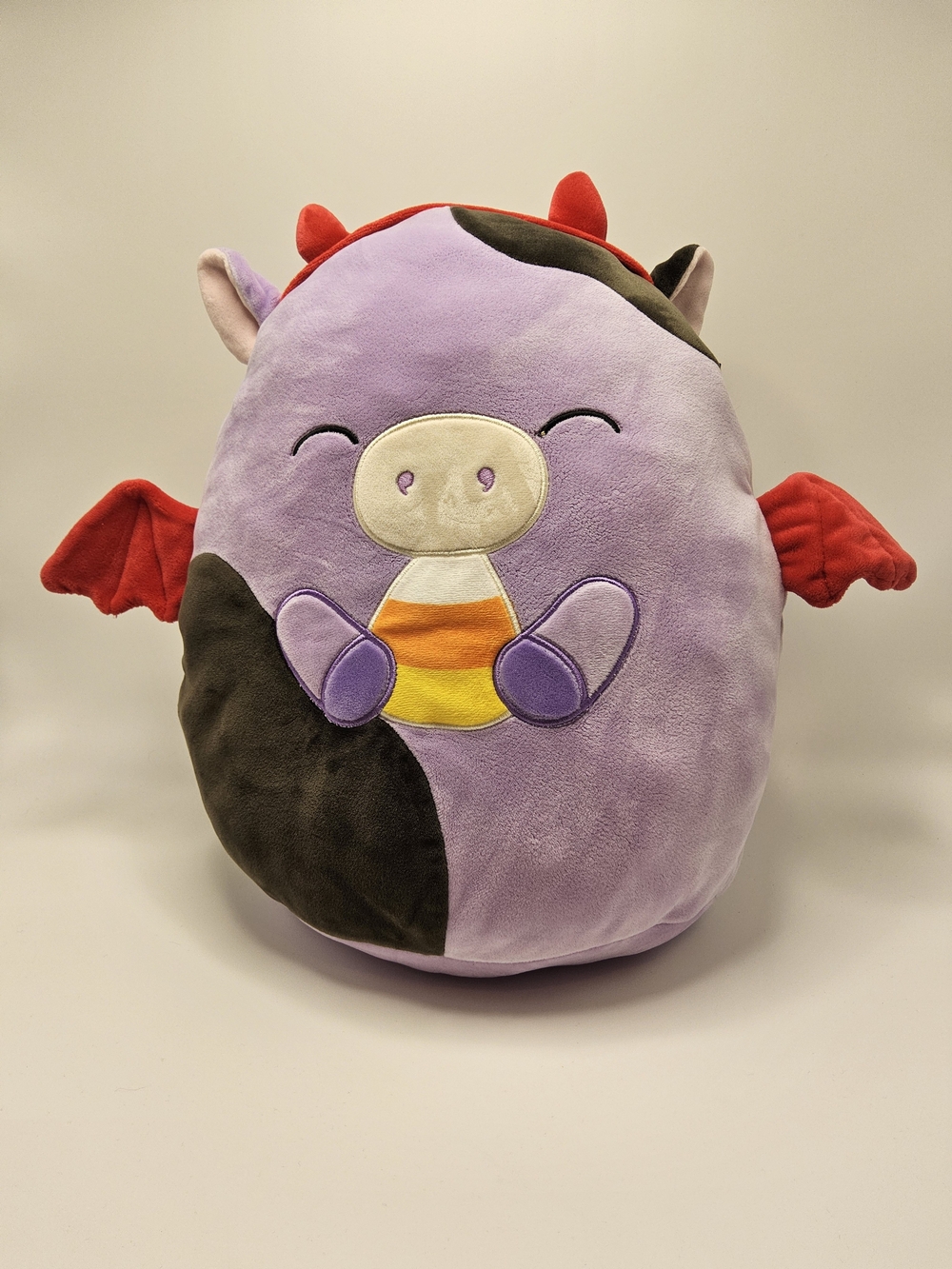 Official Squishmallows Halloween Devil Alexie the Purple Cow Holding Candy Corn